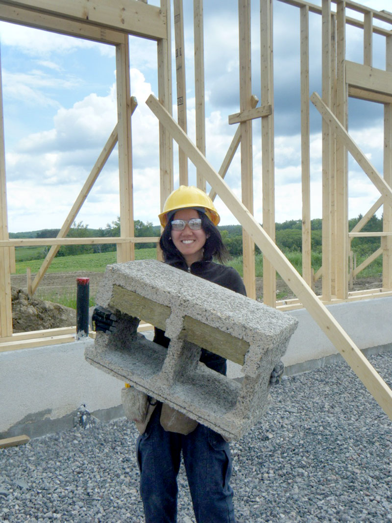 Image of young woman holding concrete brick at build site